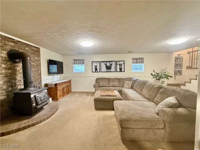 153 Lowes Dr, New Cumberland, WV 26047 - living room with light carpet, stairway, a textured ceiling, a wood stove, and a wainscoted wall