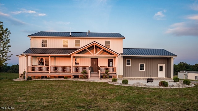 52110 Spencer Rd, Cumberland, OH 43732 - rear view of house featuring an outdoor fire pit, a standing seam roof, a lawn, a metal roof, and covered porch