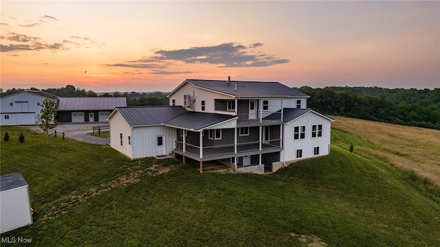 52110 Spencer Rd, Cumberland, OH 43732 - back of house at dusk featuring a metal roof, a balcony, board and batten siding, and a lawn