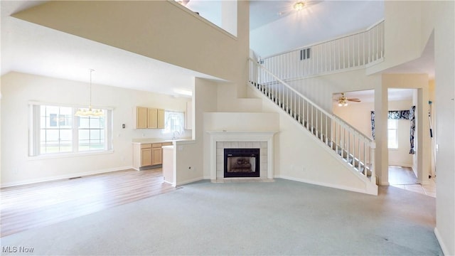 8531 Creekside Dr, Sagamore Hills, OH 44067 - unfurnished living room featuring high vaulted ceiling, stairway, light carpet, a tiled fireplace, and ceiling fan