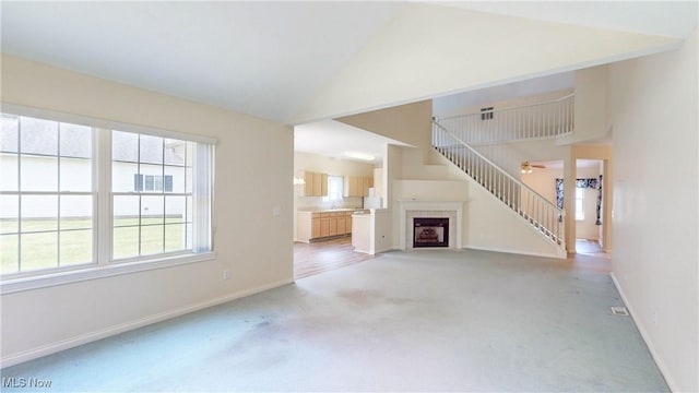 8531 Creekside Dr, Sagamore Hills, OH 44067 - unfurnished living room featuring light carpet, plenty of natural light, a tile fireplace, stairs, and high vaulted ceiling