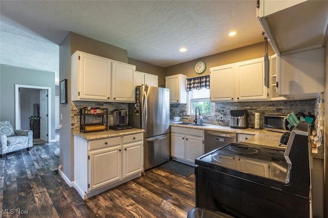 135 S 31st St, Newark, OH 43055 - kitchen with stainless steel appliances, dark wood-style floors, white cabinetry, backsplash, and a textured ceiling