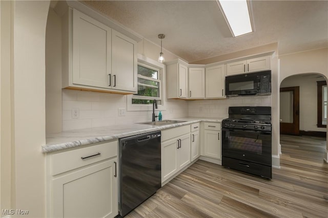 41 New St, Barberton, OH 44203 - kitchen featuring black appliances, arched walkways, light wood-type flooring, tasteful backsplash, and white cabinets
