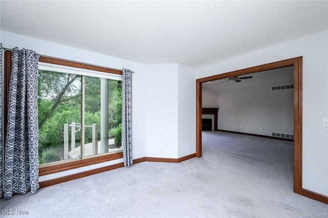 1137 Saint Abigail St SW, Hartville, OH 44632 - spare room featuring carpet floors, a fireplace, a ceiling fan, and a textured ceiling