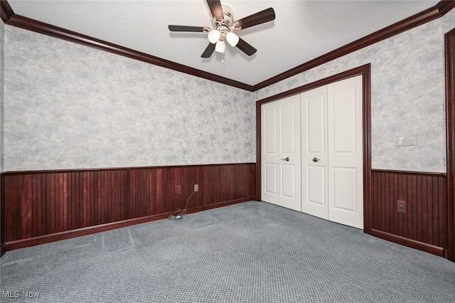 1137 Saint Abigail St SW, Hartville, OH 44632 - unfurnished bedroom featuring a wainscoted wall, wooden walls, a closet, carpet flooring, and crown molding