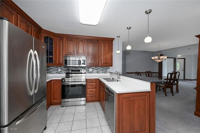 1137 Saint Abigail St SW, Hartville, OH 44632 - kitchen with appliances with stainless steel finishes, a peninsula, a chandelier, backsplash, and glass insert cabinets