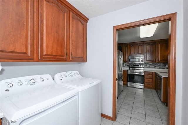 1137 Saint Abigail St SW, Hartville, OH 44632 - laundry room featuring washer and dryer, light tile patterned floors, cabinet space, and a textured ceiling