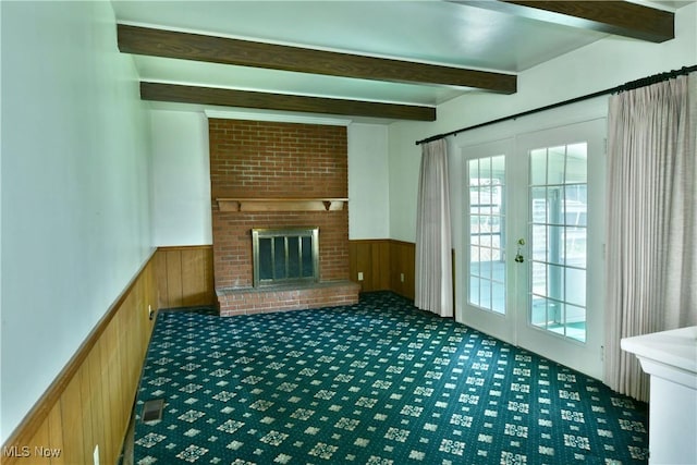 2741 Citadel Dr NE, Warren, OH 44483 - unfurnished living room with wainscoting, beam ceiling, french doors, carpet flooring, and wooden walls