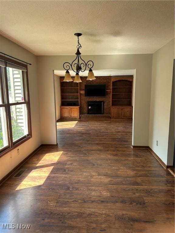 6279 Palmer Dr NW, Canton, OH 44718 - unfurnished dining area featuring a textured ceiling, dark wood-style floors, a chandelier, and a brick fireplace