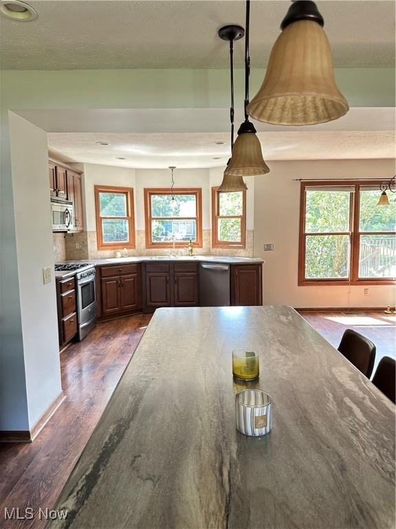 6279 Palmer Dr NW, Canton, OH 44718 - kitchen with dark wood-style floors, stainless steel appliances, decorative backsplash, pendant lighting, and stone countertops