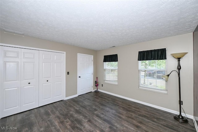 8714 Quailridge Ct, Macedonia, OH 44056 - unfurnished bedroom with dark wood-type flooring, a textured ceiling, and a closet
