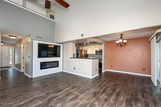 8714 Quailridge Ct, Macedonia, OH 44056 - unfurnished living room with dark wood-type flooring, a ceiling fan, a glass covered fireplace, and a chandelier