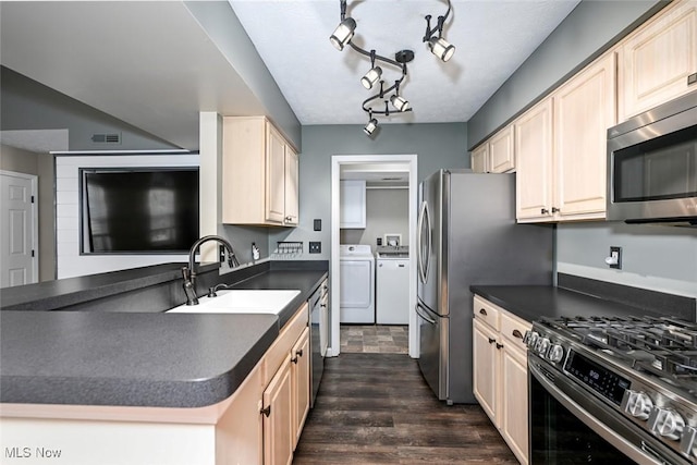 8714 Quailridge Ct, Macedonia, OH 44056 - kitchen with stainless steel appliances, washing machine and dryer, dark countertops, dark wood-type flooring, and light brown cabinetry