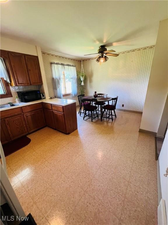 3174 Lynwood Dr NW, Warren, OH 44485 - kitchen featuring a ceiling fan, light floors, a peninsula, light countertops, and wallpapered walls