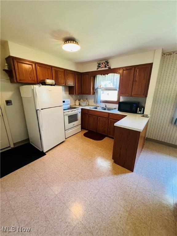 3174 Lynwood Dr NW, Warren, OH 44485 - kitchen with white appliances, a peninsula, light countertops, wallpapered walls, and light flooring