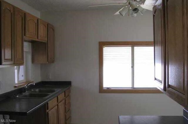 5000 Dimson Dr N, Columbus, OH 43213 - kitchen featuring ceiling fan, dark countertops, and brown cabinets