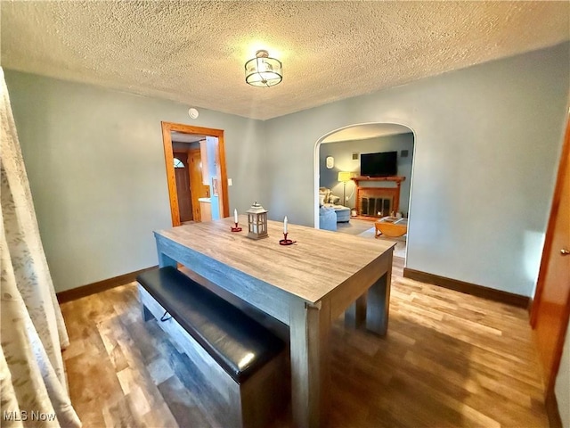 1257 Elmhurst Dr, Weirton, WV 26062 - dining area featuring arched walkways, wood finished floors, a textured ceiling, and a fireplace