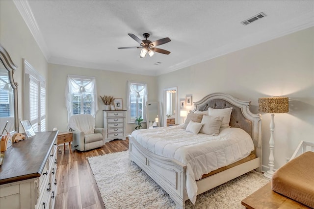 bedroom featuring ceiling fan, light hardwood / wood-style flooring, a textured ceiling, and crown molding