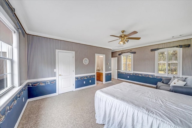 carpeted bedroom with ceiling fan, crown molding, and ensuite bath