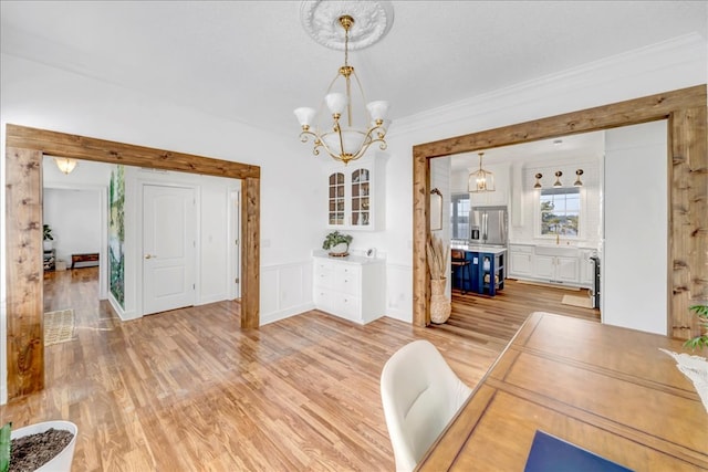 dining space with light hardwood / wood-style flooring, crown molding, and a chandelier