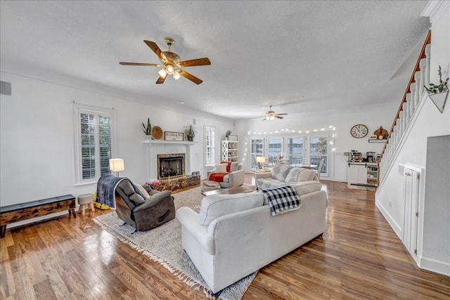 living room with hardwood / wood-style floors, a textured ceiling, ceiling fan, and ornamental molding