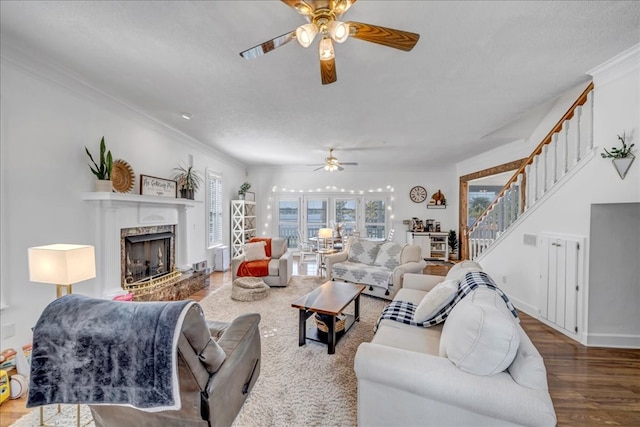 living room with crown molding, hardwood / wood-style flooring, a textured ceiling, and a high end fireplace