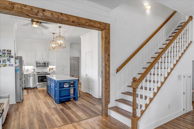 kitchen featuring appliances with stainless steel finishes, a center island, white cabinetry, hanging light fixtures, and blue cabinets