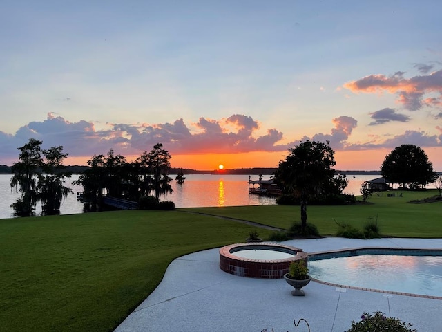 view of community featuring a dock, a water view, a hot tub, and a yard