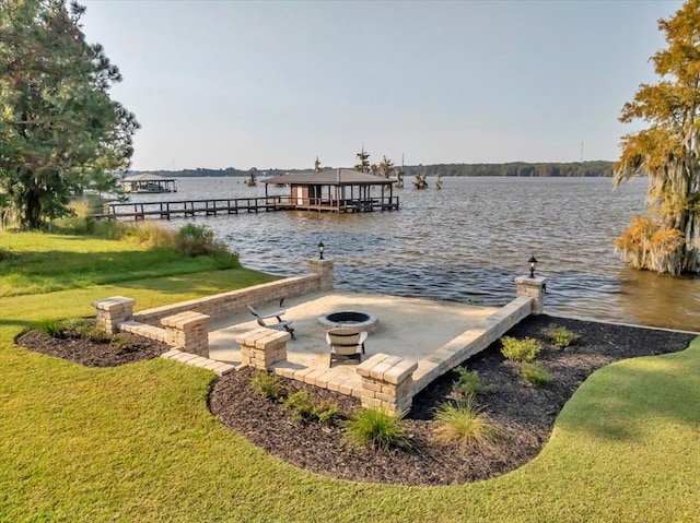 view of dock with a water view, an outdoor fire pit, and a lawn