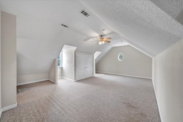 additional living space with light colored carpet, a textured ceiling, and a wealth of natural light