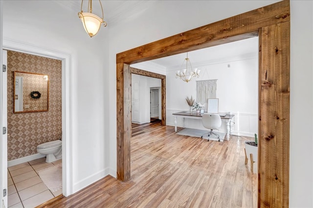 hallway featuring a notable chandelier, crown molding, and light hardwood / wood-style floors