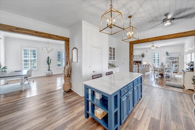 kitchen featuring light stone countertops, wood ceiling, blue cabinets, light wood-type flooring, and pendant lighting