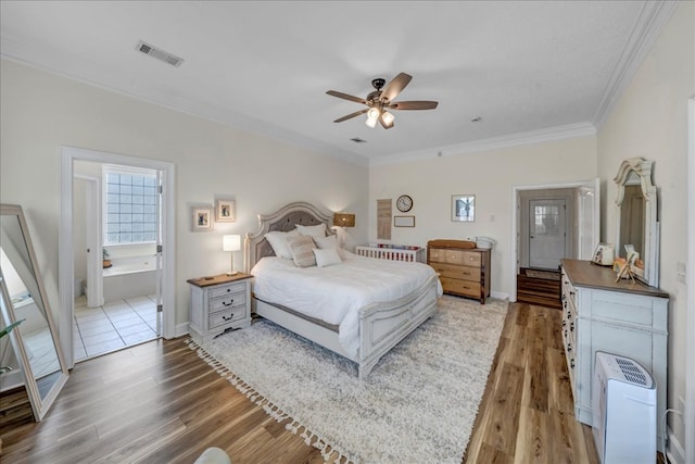 bedroom featuring crown molding, hardwood / wood-style floors, ensuite bathroom, and ceiling fan