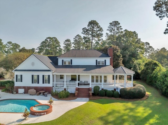 rear view of property featuring a pool with hot tub, a patio area, and a yard