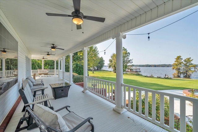 wooden deck featuring a porch, a water view, a lawn, and ceiling fan