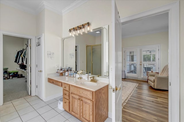 bathroom with tile patterned flooring, a shower with shower door, vanity, and ornamental molding