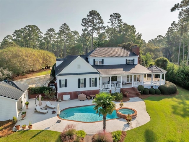 rear view of property featuring a patio area, a pool with hot tub, and a yard