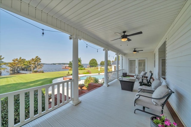 deck with french doors, a water view, ceiling fan, and a yard