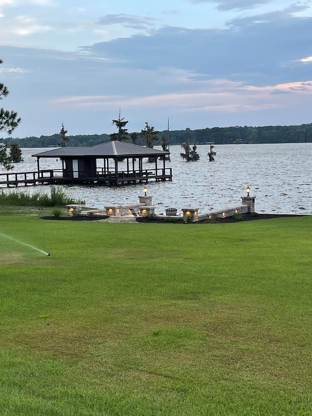 dock area with a water view and a yard