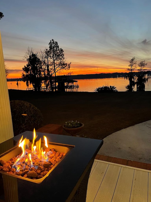 yard at dusk with a patio, a water view, and an outdoor fire pit