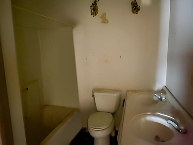 bathroom featuring sink, toilet, and a tub to relax in