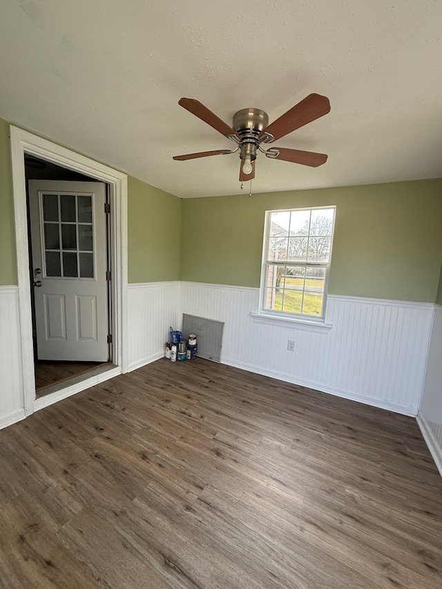 unfurnished room featuring a wainscoted wall, ceiling fan, a textured ceiling, and wood finished floors