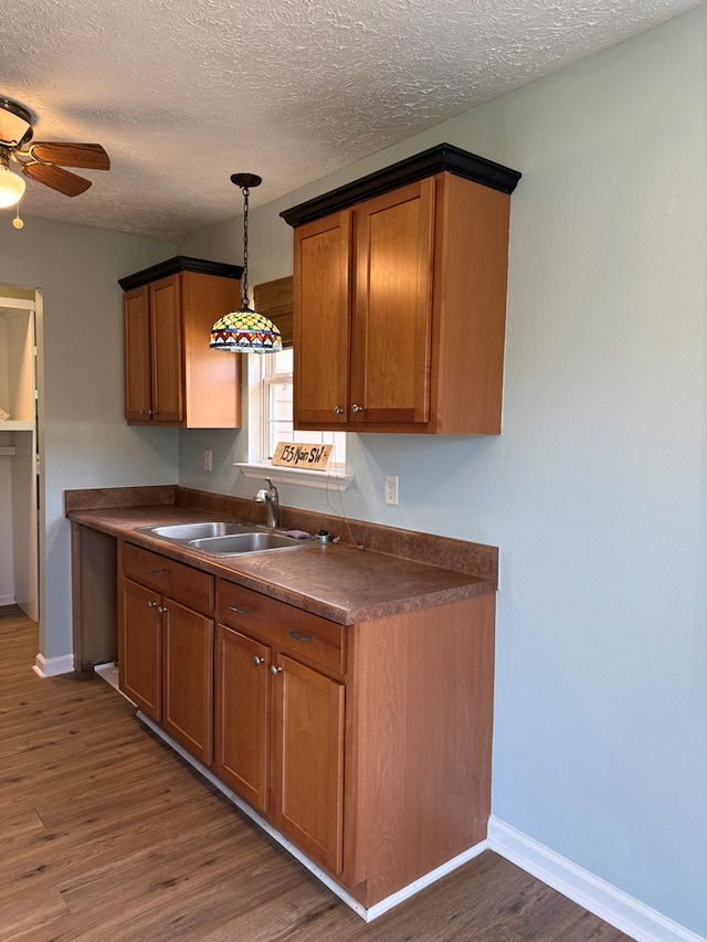 kitchen with dark countertops, dark wood-style floors, brown cabinets, and a sink