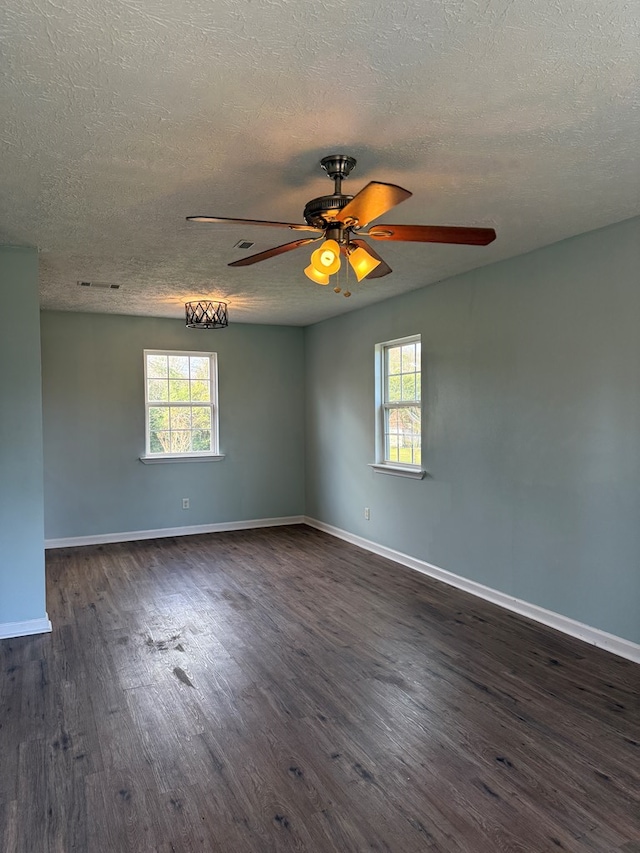 unfurnished room with ceiling fan, dark wood-type flooring, a textured ceiling, and baseboards