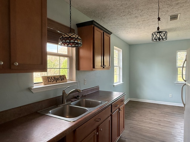 kitchen featuring dark wood finished floors, a sink, visible vents, and pendant lighting