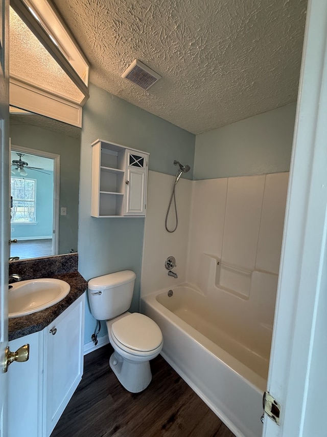 full bathroom with visible vents, toilet, vanity, a textured ceiling, and wood finished floors