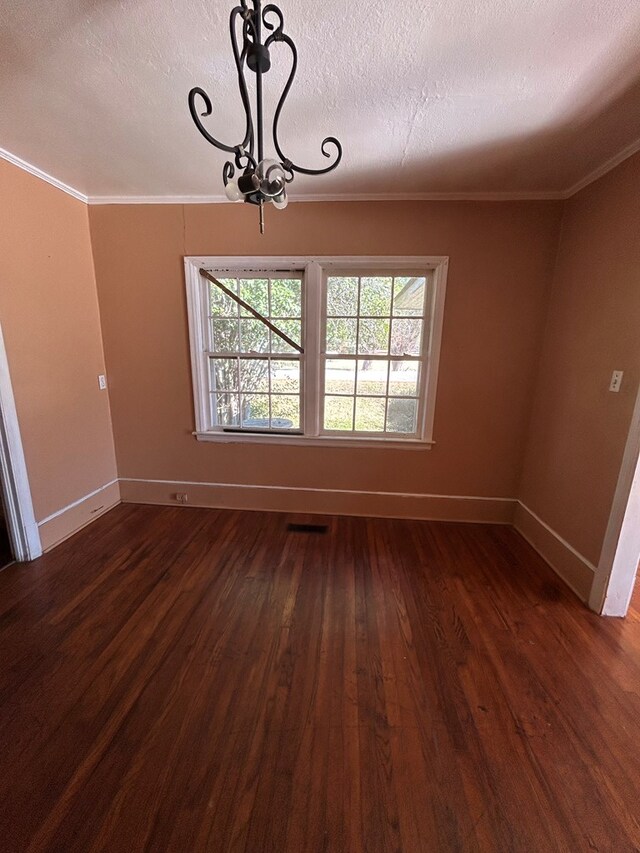 unfurnished dining area featuring a textured ceiling, dark wood-type flooring, and crown molding