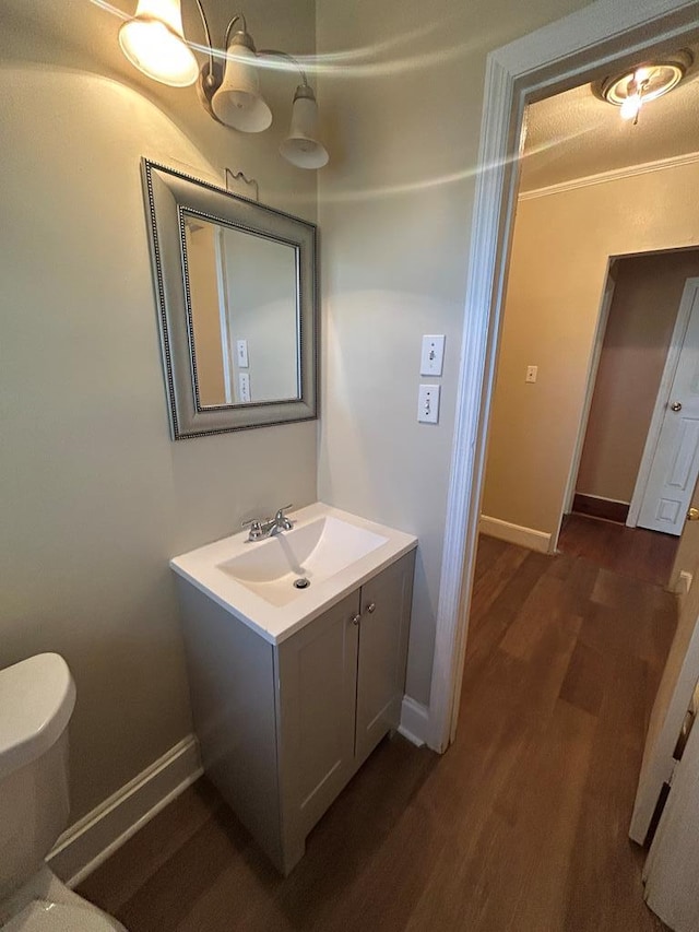 bathroom featuring ornamental molding, vanity, toilet, and hardwood / wood-style floors