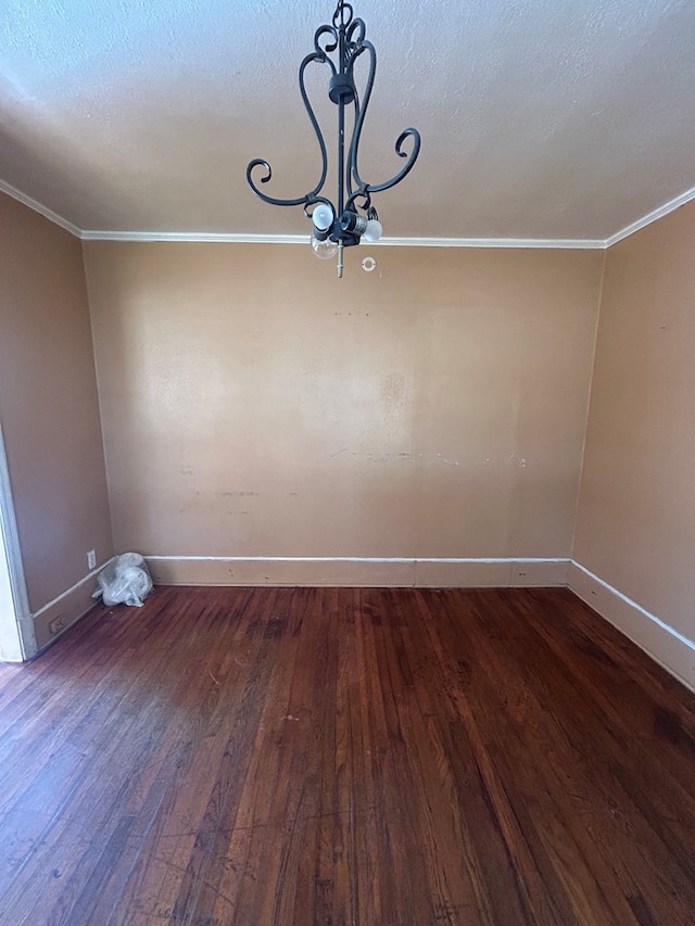 spare room with a textured ceiling, dark wood-type flooring, and crown molding