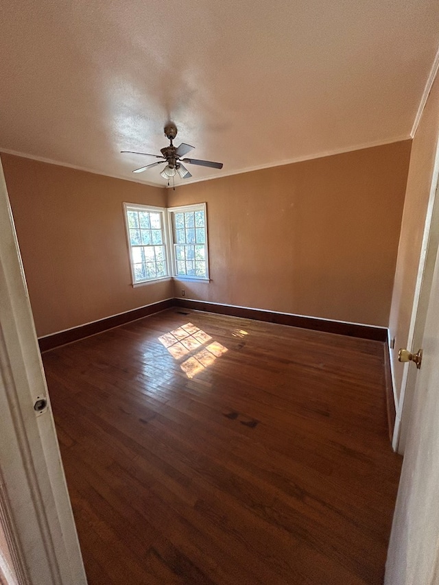 spare room featuring ceiling fan, dark wood-type flooring, and crown molding